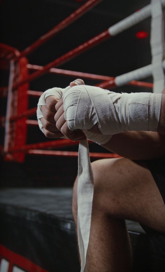 Fighter's wrapped hands on the ropes